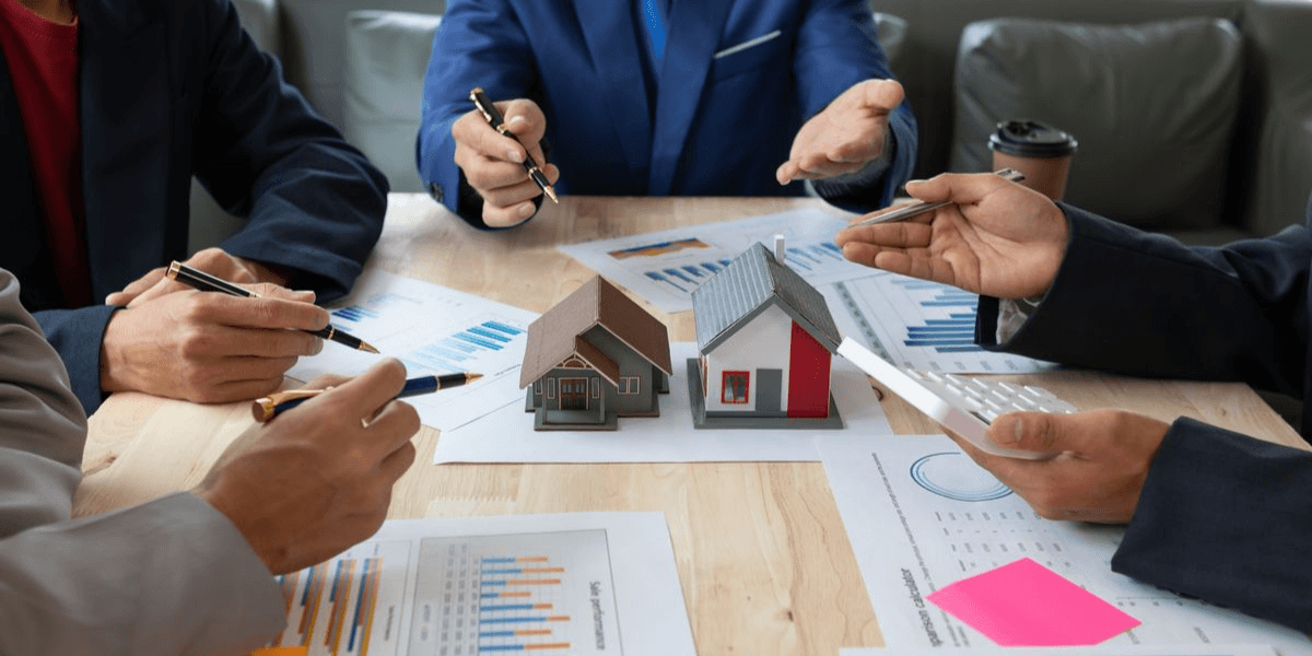 Group of people discussing real estate models and charts at a meeting table