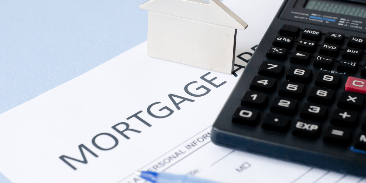 Mortgage application form, calculator, silver house model, and blue pen on a table