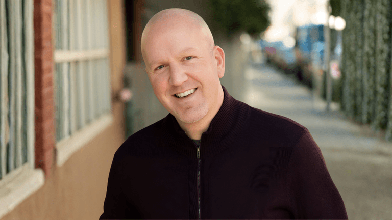Ryan Weible, Bay Area Realtor, smiling in a professional setting with a city street in the background.
