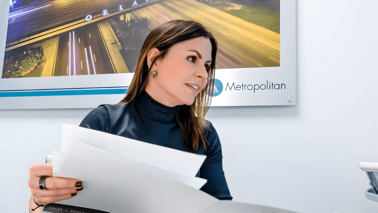 Alejandra Silva reviews real estate documents at Metropolitan Real Estate Solutions office in Florida.