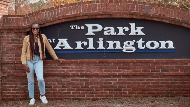 Dr. Nkem Ezeamama standing beside The Park at Arlington community sign.
