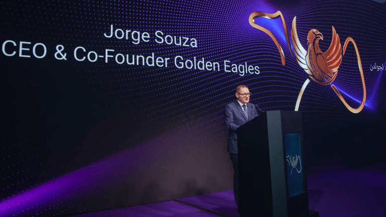 Jorge Souza speaks at event with Golden Eagles logo, highlighting global business expansion and strategic partnerships.
