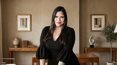 Woman in a black dress poses confidently in a stylish interior setting
