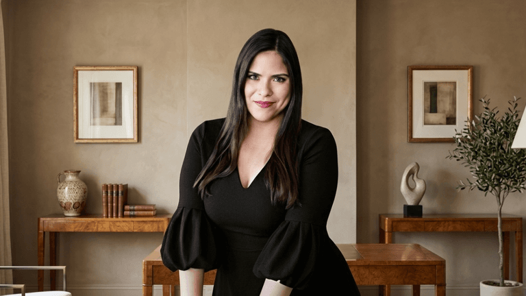 Woman in a black dress poses confidently in a stylish interior setting