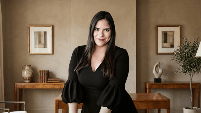 Woman in a black dress poses confidently in a stylish interior setting