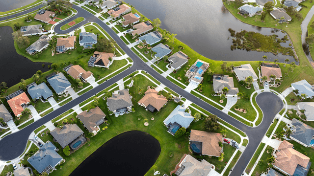 Aerial view of a suburban neighborhood with houses, roads, and ponds.