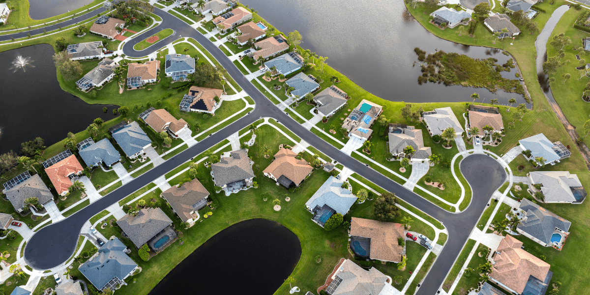 Aerial view of a suburban neighborhood with houses, roads, and ponds.