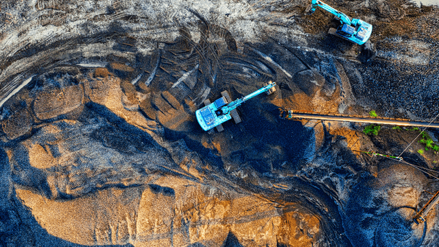 Aerial view of excavation machinery working on a gravel site with patterns in the earth