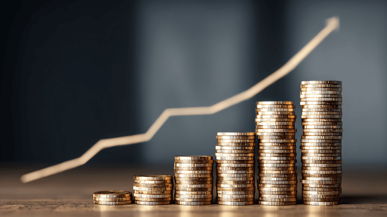 Stacks of coins with a rising graph line in the background symbolizing growth