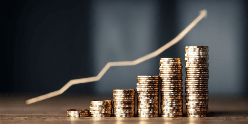Stacks of coins with a rising graph line in the background symbolizing growth