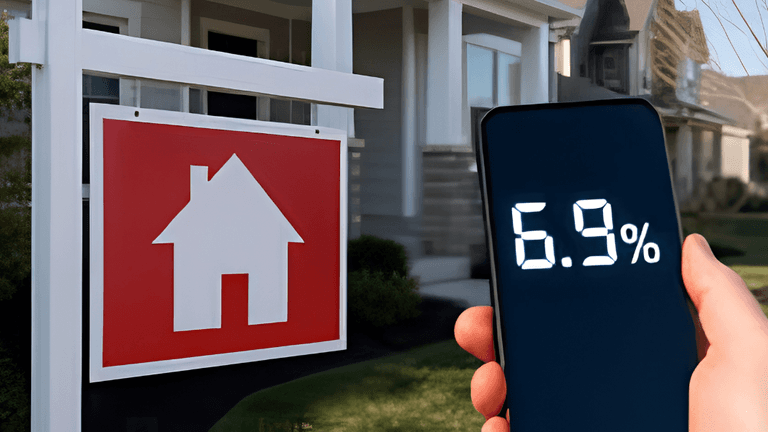 Hand holding a smartphone displaying 6.9% next to a for-sale house sign
