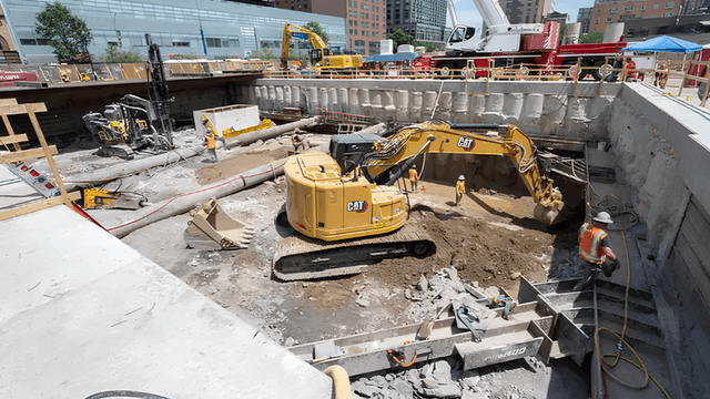 Construction site with excavators, workers, and machinery in a large excavation area