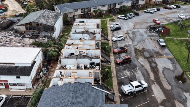 Aerial view of storm-damaged buildings and parked cars in a residential area